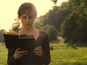 Young woman reading book, standing, in nature