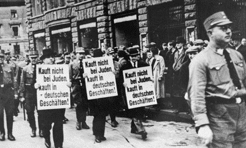 Jewish businessmen are forced to march on Bruehl Strasse, one of the main commercial streets in central Leipzig, carrying signs that read, "Don't buy from Jews. Shop in German businesses!" 1935. Photo credit: William Blye Collection, courtesy of USHMM Photo Archives