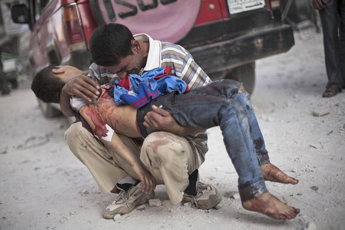 A Syrian man holds lifeless body of his son, killed by Syrian Army, Aleppo, Syria, October 3, 2013, photo by Manu Brabo - AP